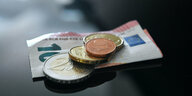 Münzen und ein Geldschein im Wert von 12,41 Euro liegen auf einer schwarzen Fläche